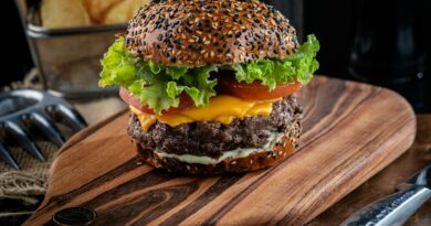 Close-up of a delicious cheeseburger with sesame seed bun and toppings on a wooden board.