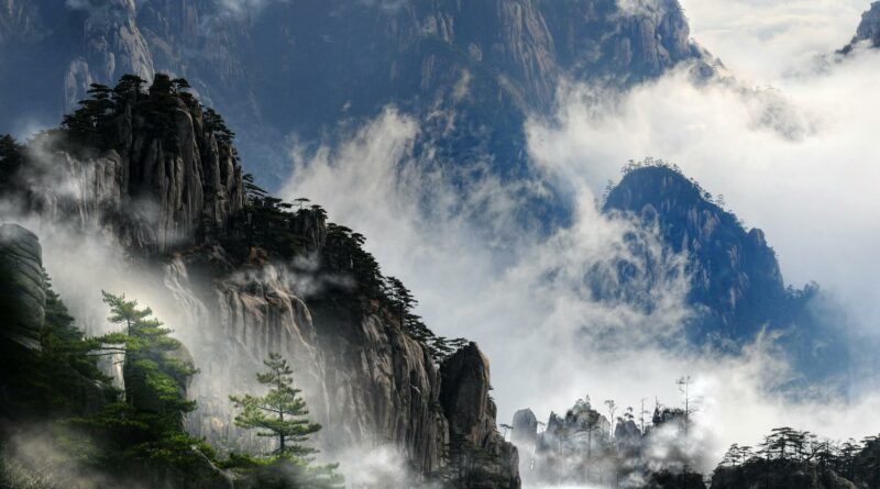 Misty mountain peaks of Huangshan, China enveloped in fog, creating a serene and dramatic landscape.