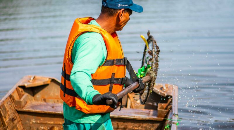 A worker cleaning a lake in Londrina, Brasil, wearing a life vest and using a net.