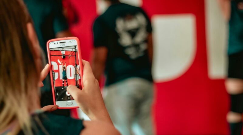 A woman captures a moment at an event on her smartphone indoors.