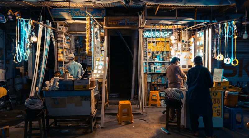 Colorful street market in Faisalabad at night, showcasing local vendors and vibrant lights.