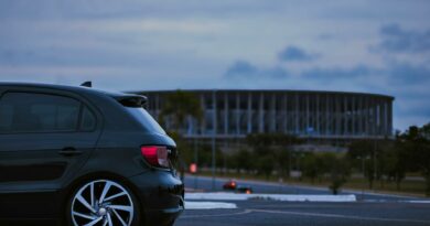 A black car parked near the iconic Estádio Nacional in Brasília at twilight.