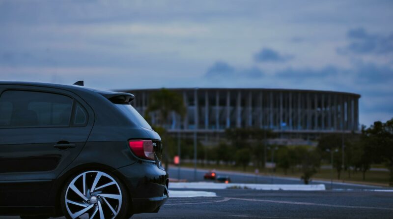 A black car parked near the iconic Estádio Nacional in Brasília at twilight.