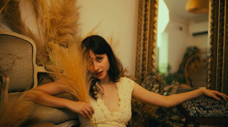 Elegant woman in vintage setting with dried plants, reflecting a warm, relaxed mood.