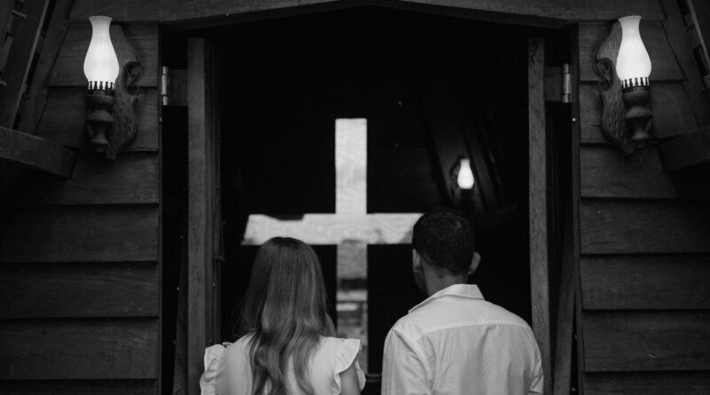 Couple seen from behind entering a church with a cross in Paragominas, Brazil.