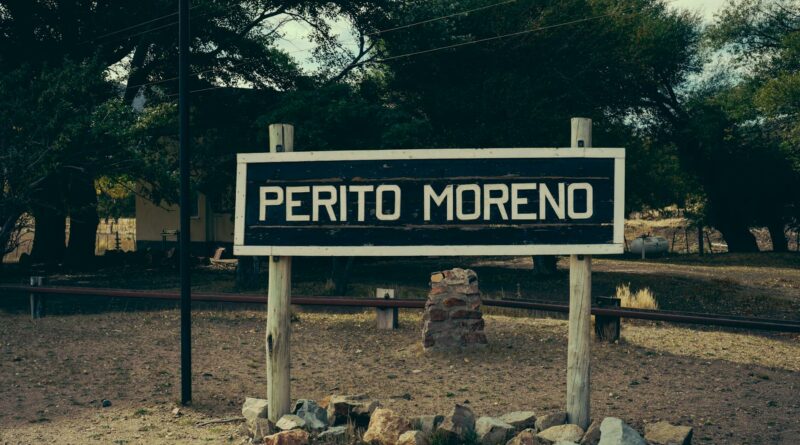 A classic wooden sign for Perito Moreno, captured in a rural setting in Argentina.