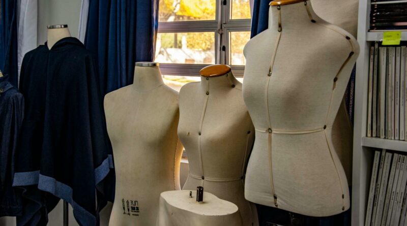 A glimpse into a fashion design studio featuring dress forms against a window backdrop.