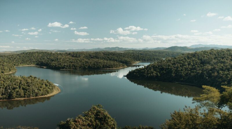 A picturesque view of a serene river winding through lush forests in Minas Gerais, Brazil.