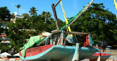 A vibrant traditional fishing boat rests on a beach in Rio Grande do Norte, Brazil.