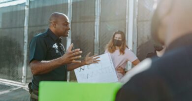 A police officer converses with protesters holding signs outdoors, demonstrating active communication.