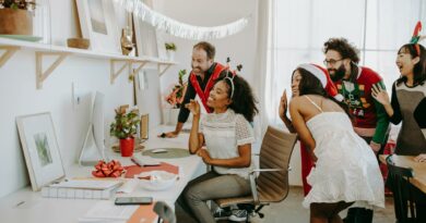 Diverse group enjoying a virtual holiday party in a decorated office environment.