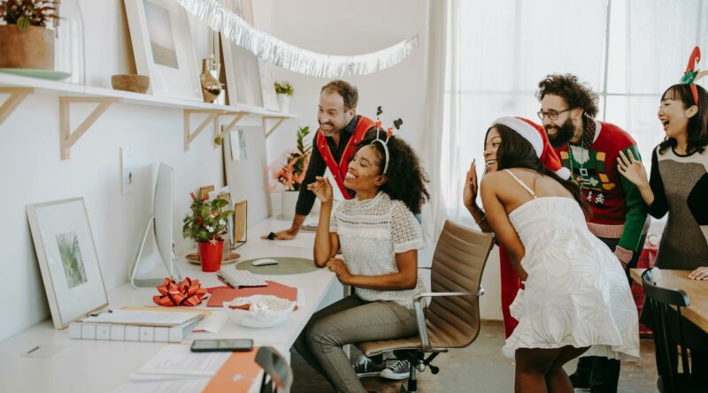 Diverse group enjoying a virtual holiday party in a decorated office environment.