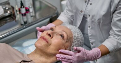 A mature woman in a spa receiving a relaxing facial treatment from a professional in a medical clinic setting.
