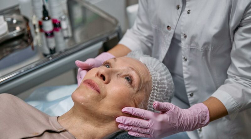 A mature woman in a spa receiving a relaxing facial treatment from a professional in a medical clinic setting.