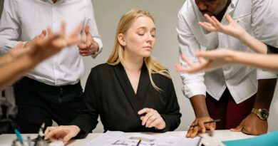 Team of professionals in a tense office discussion around a desk with documents.
