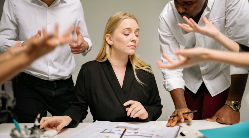 Team of professionals in a tense office discussion around a desk with documents.