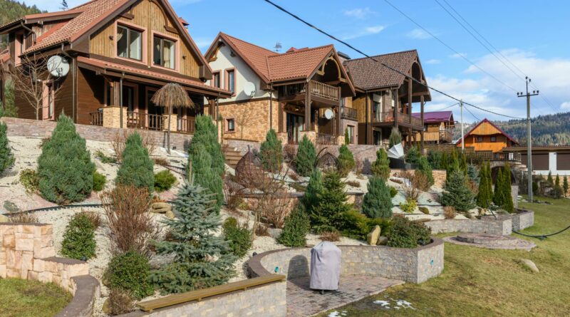 Rustic houses with sloped roofs and landscaped gardens under clear blue skies. Ideal for real estate visuals.