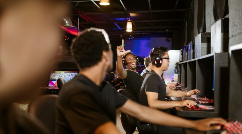 Excited gamers in an arcade setting enjoying a LAN party together, showcasing teamwork and fun.