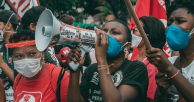 Protesters in masks advocate for rights in Rio de Janeiro amid political unrest.