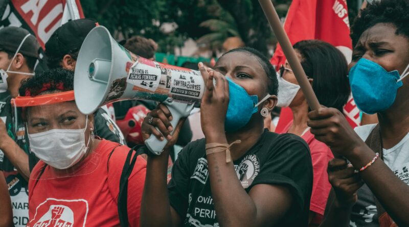 Protesters in masks advocate for rights in Rio de Janeiro amid political unrest.