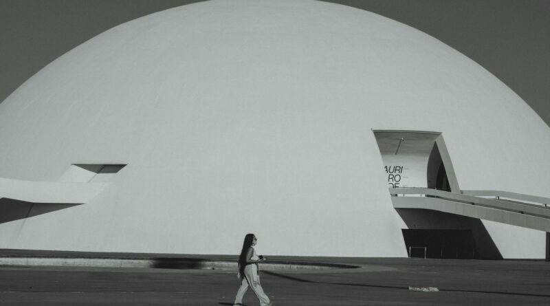 A woman walks by the futuristic Niemeyer Dome in Brasília, showcasing modern architecture.