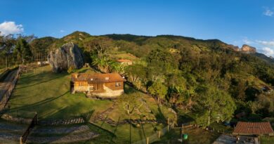 A serene aerial view of São Bento do Sapucaí's countryside, featuring a quaint house against a lush mountain backdrop.