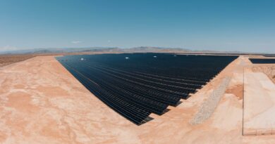 Aerial view of a large solar farm in a desert setting under a clear blue sky.