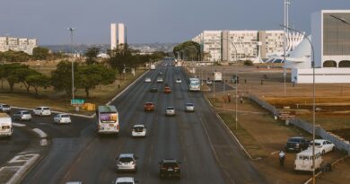 Aerial view of Brasília's urban traffic with prominent government buildings and a bustling road.