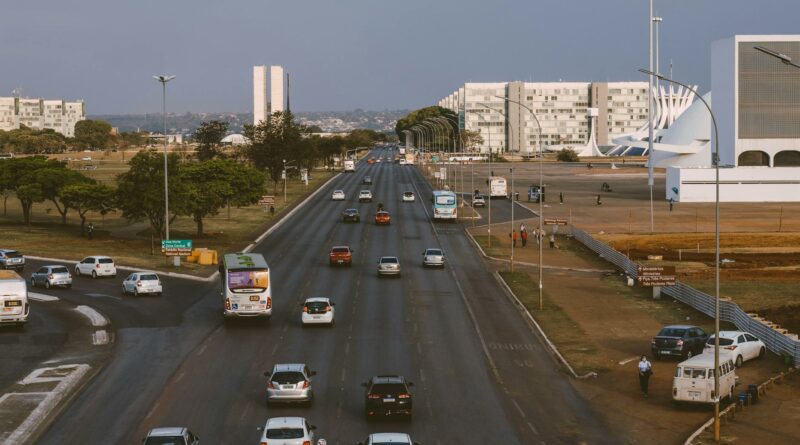 Aerial view of Brasília's urban traffic with prominent government buildings and a bustling road.