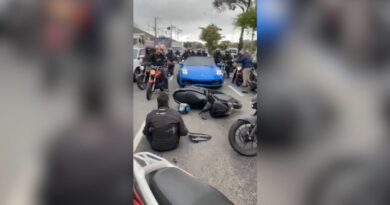 Carro esportivo de luxo, modelo Porsche, parado em uma avenida movimentada após um acidente de trânsito.