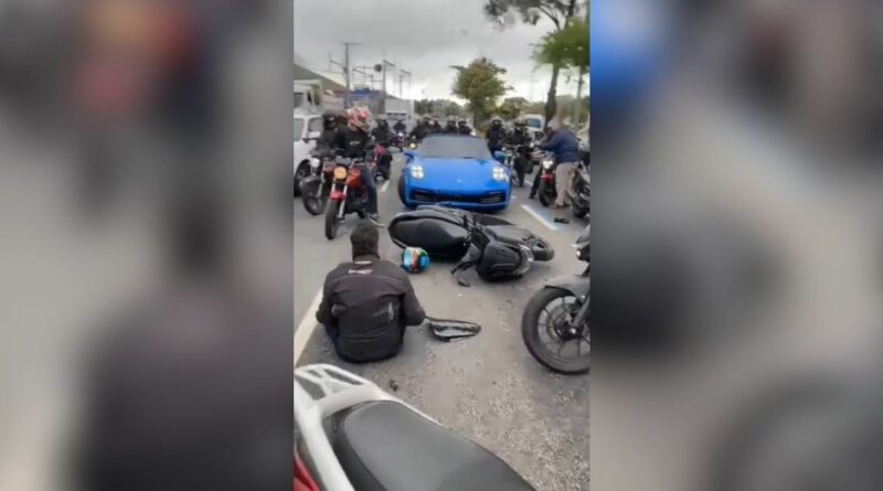 Carro esportivo de luxo, modelo Porsche, parado em uma avenida movimentada após um acidente de trânsito.