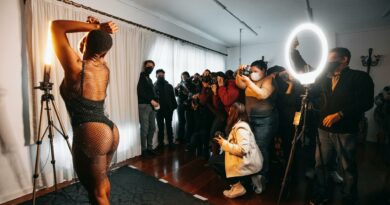 Photographers capturing a model in an indoor studio setup during a fashion workshop.