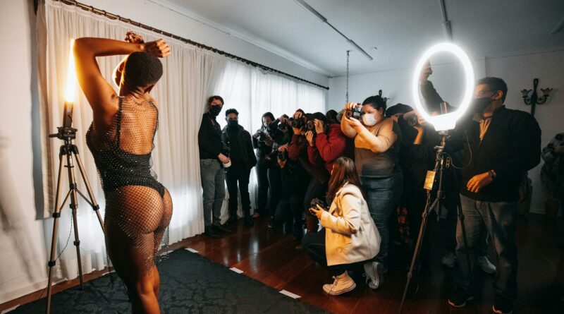 Photographers capturing a model in an indoor studio setup during a fashion workshop.