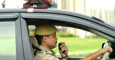 Uniformed police officer using a radio inside a moving patrol car.