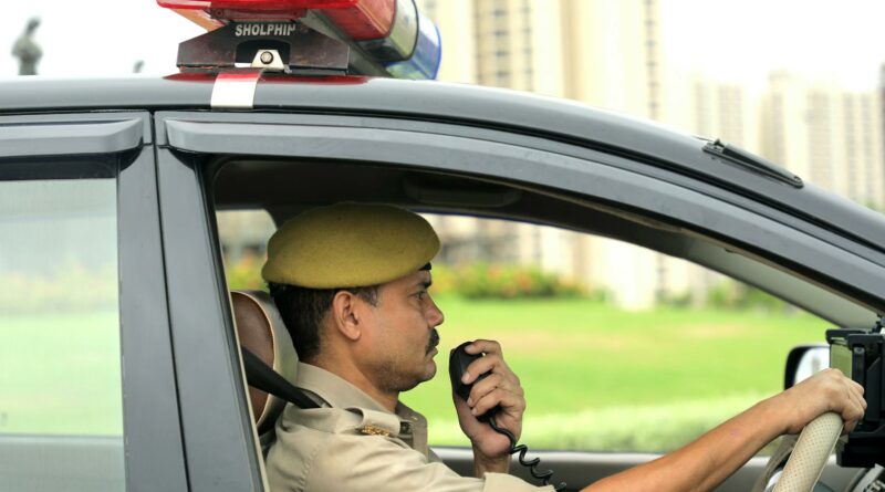 Uniformed police officer using a radio inside a moving patrol car.
