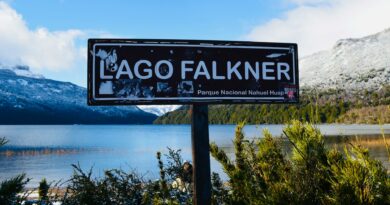 A serene view of Lago Falkner in Parque Nacional Nahuel Huapi, Argentina, with snow-capped mountains.