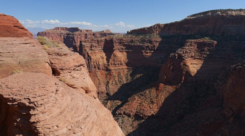 Dramatic view of a red rock canyon and mesas under a clear blue sky.
