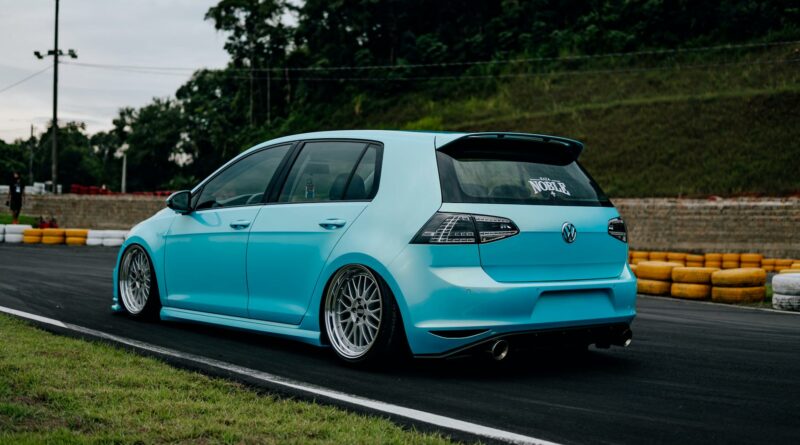 A stanced blue VW Golf parked on a race track in Brazil, showcasing aftermarket modifications.