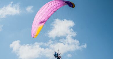 Experience the thrill of tandem paragliding with colorful parachute soaring high in the clear blue sky.