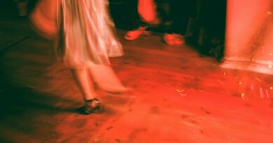 Blurred image capturing the dynamic motion of dancing in vibrant red lighting.