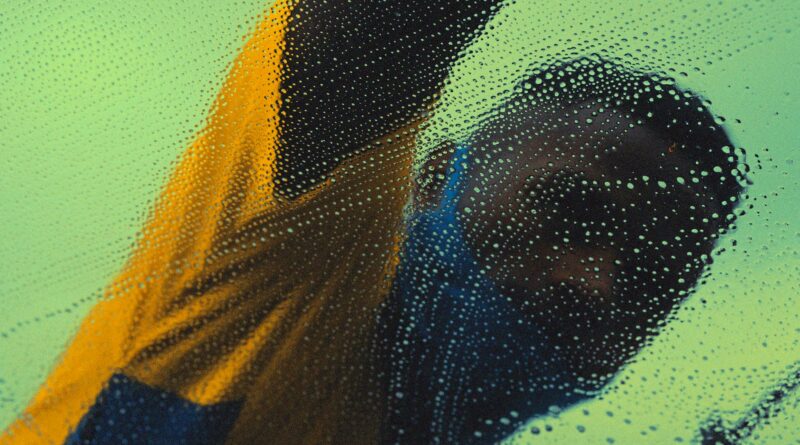 Anonymous man in São Paulo washing glass with soap and bubbles, creating a blurred effect.