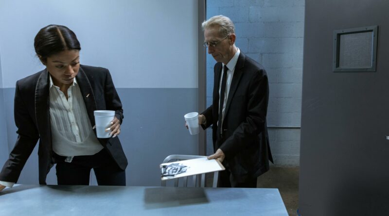 Two professionals in a secure office setting discussing confidential documents over coffee.