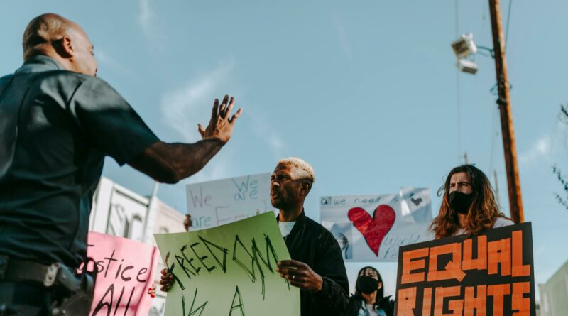 A group of protesters holding signs for freedom and equal rights during a daytime demonstration.