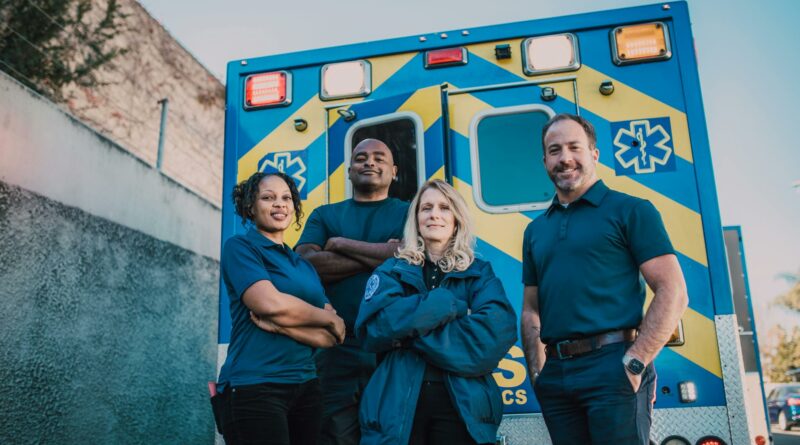 Paramedic team stands confidently in front of an ambulance, ready for emergencies.