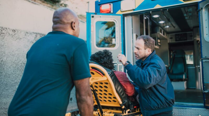 First responders assisting a patient into an ambulance for medical aid.
