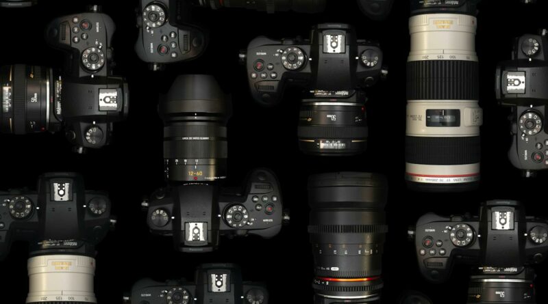 A collection of DSLR cameras and lenses against a black backdrop, showcasing modern photography equipment.