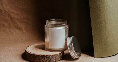 A minimalist candle in a glass jar with a metal lid, set on a wooden slice, creating a cozy ambience.