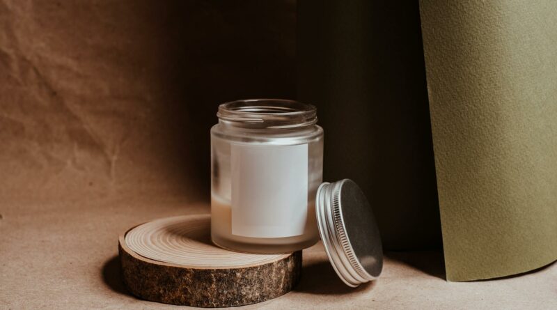 A minimalist candle in a glass jar with a metal lid, set on a wooden slice, creating a cozy ambience.
