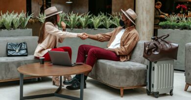 Two fashionable individuals shaking hands in a hotel lobby, showcasing travel and safety.