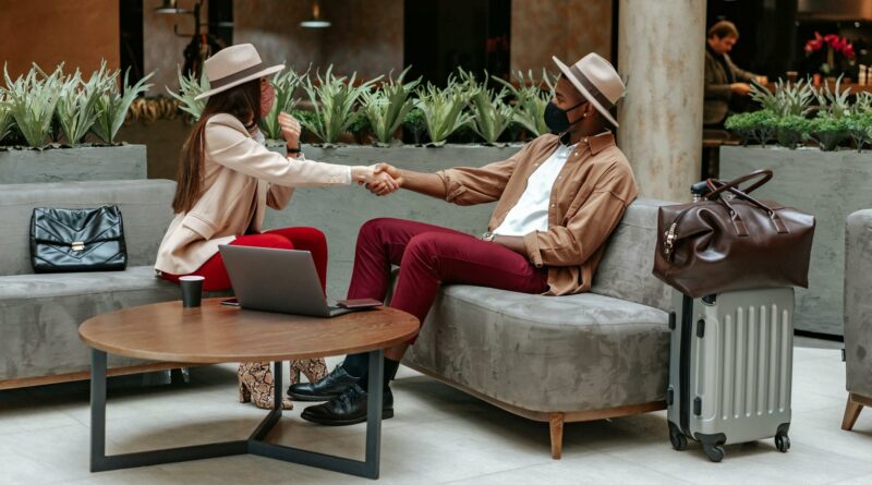 Two fashionable individuals shaking hands in a hotel lobby, showcasing travel and safety.